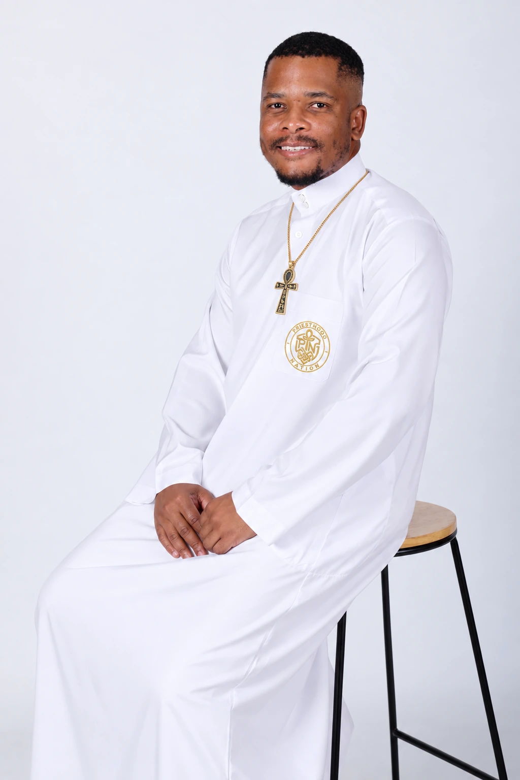 Portrait of Phiwa Nkambule wearing a gold ankh necklace and Priesthood Nation embroidered pocket crest